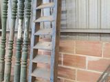 une échelle appuyée contre un mur de briques, à côté d'un tas de vieux outils