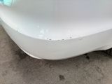 a close up of a white car with a denting on it