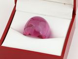 a pink glass ball in a red box on a white surface