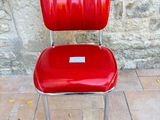 a red chair with a label on it sitting in front of a stone wall