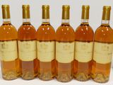 six bottles of wine are lined up in a row on a white surface