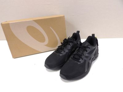 the black sneakers are next to a box on a white surface
