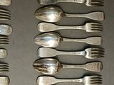 many forks and spoons laid out on a table