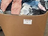 un carton rempli de vêtements et d'autres objets posé sur une palette