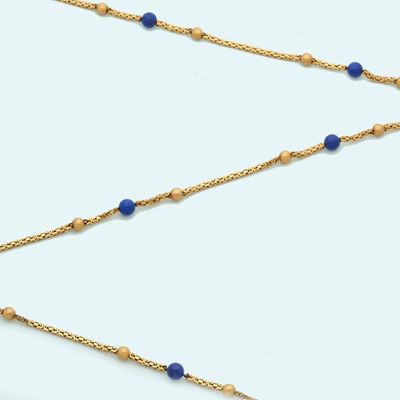 a close up of a gold chain with blue beads on it