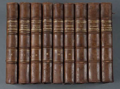 six vieux livres alignés en rangées sur une surface grise
