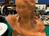 un buste de femme assise sur une table à côté d'une machine à coudre
