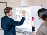 a man and a woman standing in front of a whiteboard