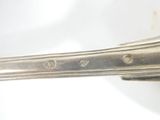 a silver spoon with a handle on a white surface