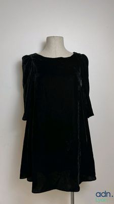black velvet dress on a mannequin stand against a white wall