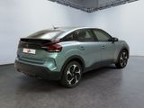 the rear end of a blue car in a room with a white wall