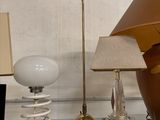 une étagère en verre sur laquelle sont posés une lampe, un abat-jour et un vase