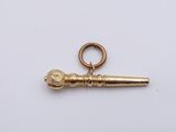 an image of a small gold key charm on a white surface