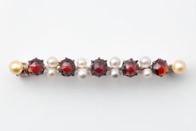 a close up of a red and white pearl and garnett broochle