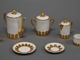 une image représentant un service à thé blanc et doré, composé de tasses et de soucoupes