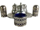 a silver tea set with a blue glass in it