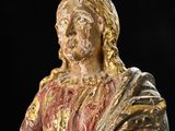 an old statue of jesus holding a cross on a black background