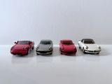 quatre petites voitures sont alignées sur une surface blanche