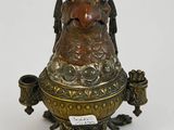 une image représentant un grand vase en bronze et de couleur bronze, orné d'un oiseau sur le col