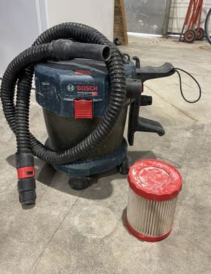 un aspirateur posé par terre à côté d'un bac de collecte