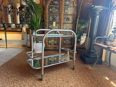 a metal cart with glass shelves in the middle of a room