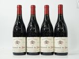 quatre bouteilles de vin rouge sont alignées sur une table