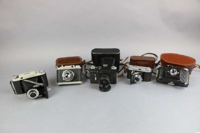 several old cameras are lined up in a row on a white surface
