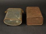 pair of old metal boxes on a black surface with a black background