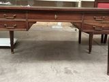 un bureau en bois avec un plateau en verre et des chaises rouges