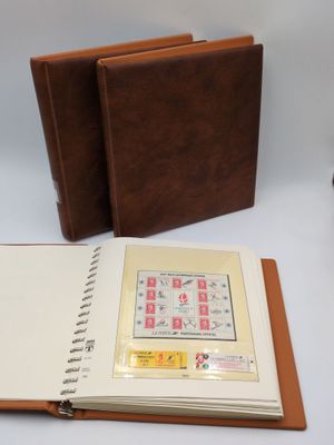 two brown leather notebooks sitting on top of a table next to a camera