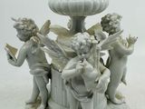 un vase blanc orné d'anges, posé sur un socle