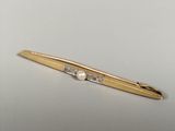a close up of a gold tie bar with a pearl on it