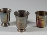 trois tasses en argent posées l'une à côté de l'autre sur une surface blanche