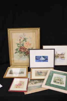 several framed and unframed art pieces are displayed on a black table