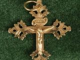 gold plated cross with a crown on top of it on a green surface