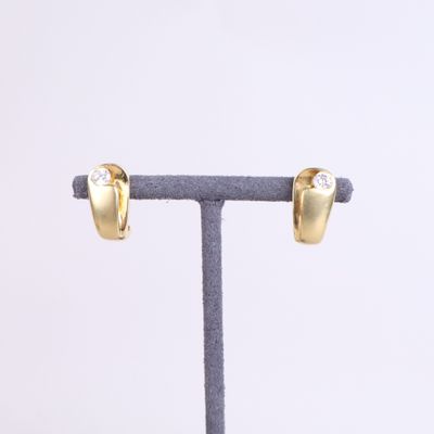 a close up of a pair of gold earrings on a stand
