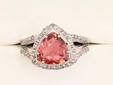 a close up of a pink diamond ring on a white surface