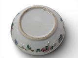 a white bowl with flowers on it on a white surface