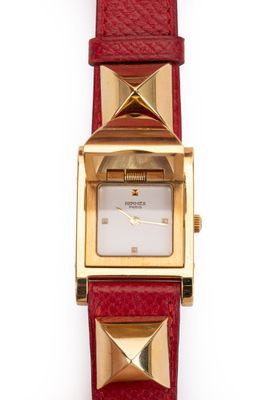 une image représentant une montre dorée et rouge sur fond blanc