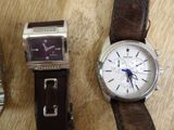 two watches sitting on a wooden table next to each other