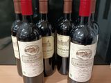 Quatre bouteilles de vin rouge sont alignées sur une table en bois