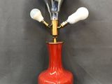 une photo d'une lampe en forme de vase rouge avec un pied en laiton