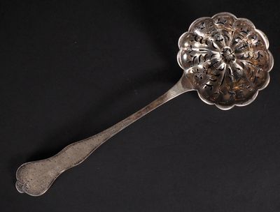 une cuillère en argent ornée d'une fleur, posée sur un fond noir