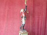 a statue of a man holding a candelier on top of a table