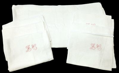 quatre serviettes blanches ornées de broderies roses sur fond noir
