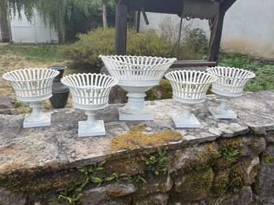 four white vases sitting on a stone wall