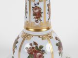 a white and gold vase on a saucer on a plate