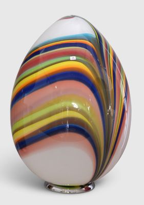 brightly colored glass egg sitting on a metal stand on a white surface