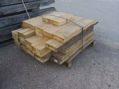 Plusieurs morceaux de bois sont empilés sur une palette dans un parking