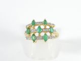 a close up of a green and white diamond ring on a white surface